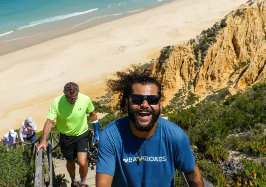 Man with blue shirt climbing up a flight of stairs on the beach
