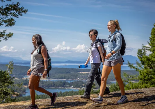 Group of three women hiking down a dirt path on a hill