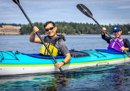 Two men in a kayak paddling in the middle of a lake