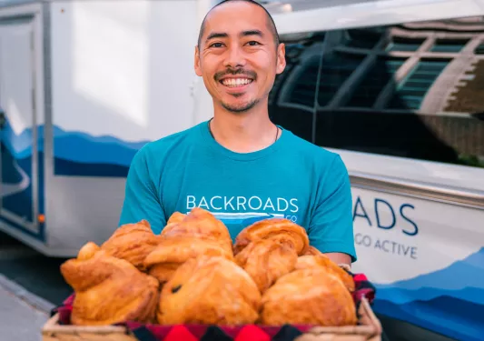 Man holding large basket of croissants