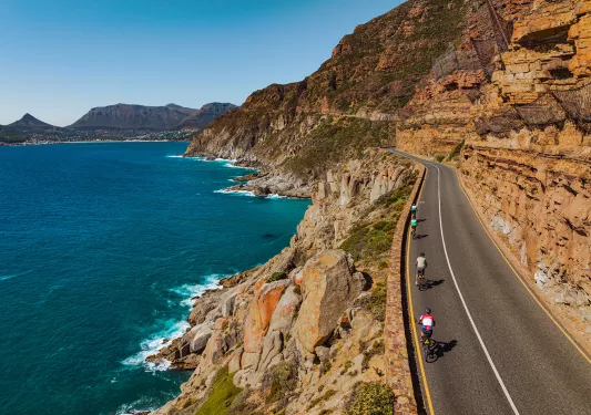 people riding bicycles down a beachfront road