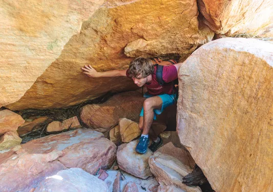 A hiker climbs through rocks