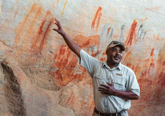 A man points to cave paintings on a wall