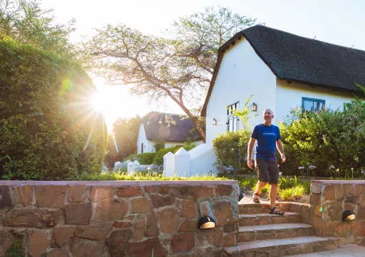 Man walking down a small stairway, with small villas behind him