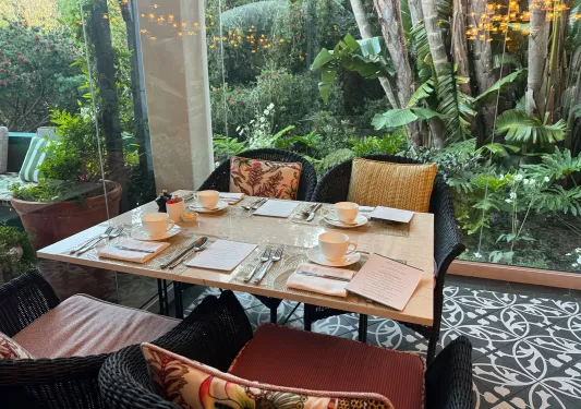 Dining table with coffee cups and black, woven chairs surrounding the table