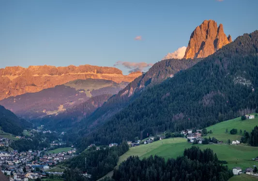 View of large hills covered in trees, with tall mountains in the distance