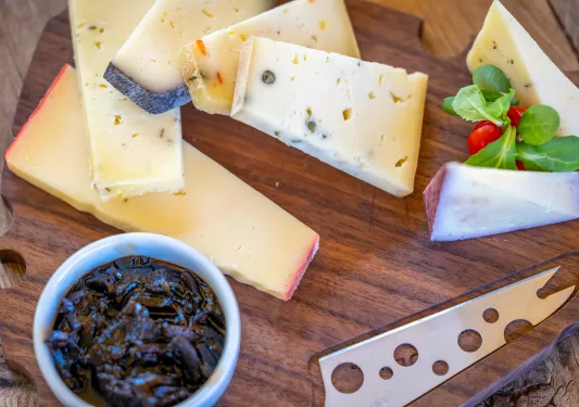 Wooden plank full of cheese and a bowl of dates