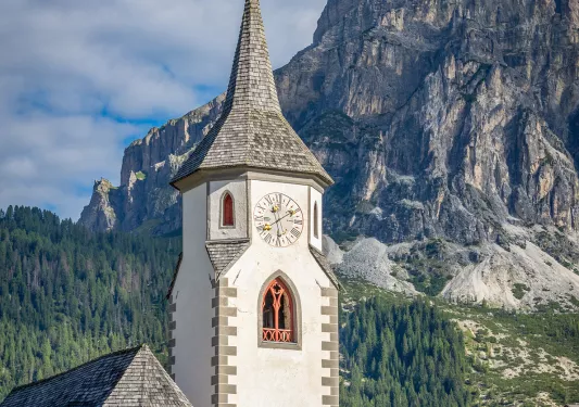 Clock tower with giant mountains and trees in the distance