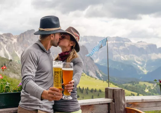 Man and woman kissing while holding up glasses of beer