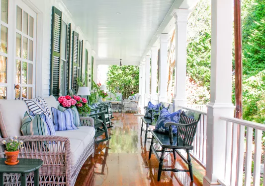 Outdoor porch of a white building with cushioned reclining chairs