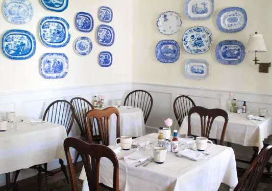 Dining hall with wooden chairs and blue and white plates hanging on the wall