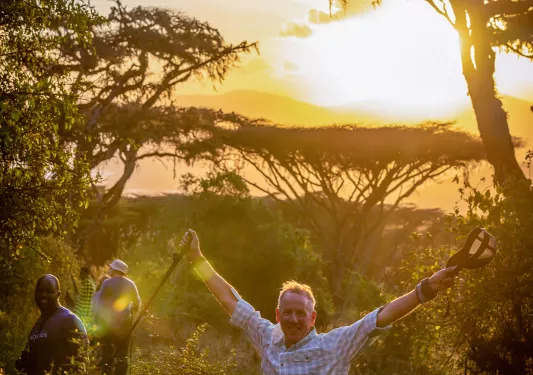 a man poses in front of a sunset