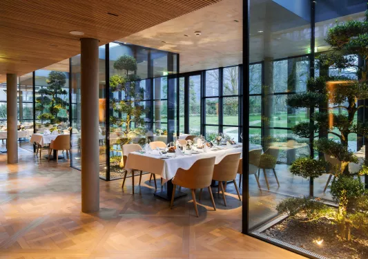 Indoor dining area with 5 long dining tables and trees in glass containments