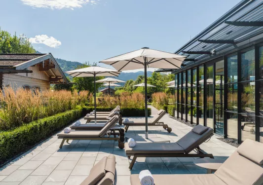 Outdoor patio with tan pool chairs and towels with open umbrellas