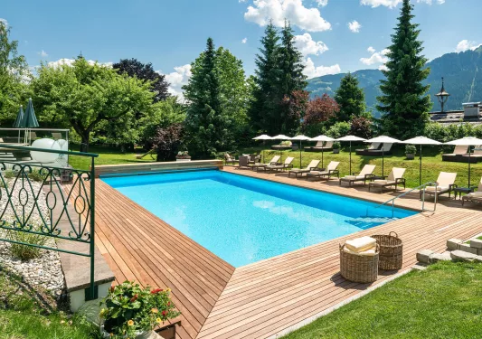 Outdoor pool surrounded by reclining chairs and umbrellas