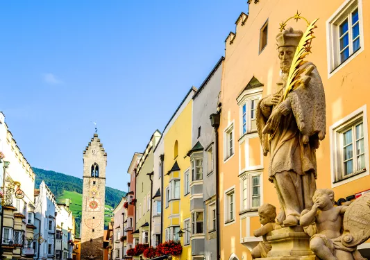 Spanish-style statue in a town center with a clocktower in the background