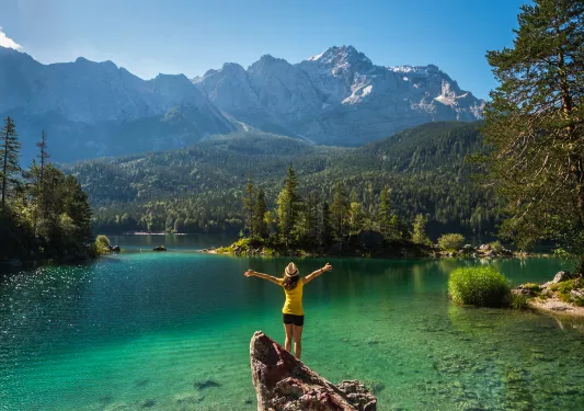 Lady standing on a rock in the middle of a lake
