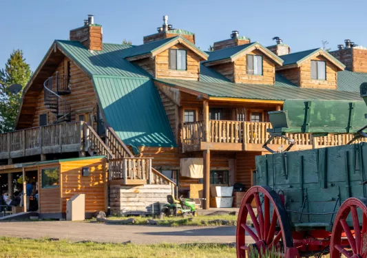 Wood cabin with a green roof, and a green wagon in front