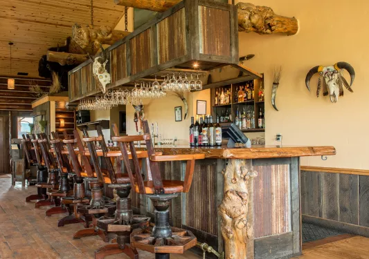 Wooden bar with wooden bar stools, with dried bull skulls hanging on the wall
