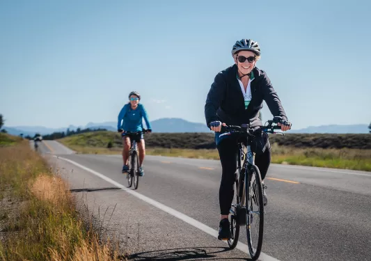 Two people biking along a road in Tetons National Park