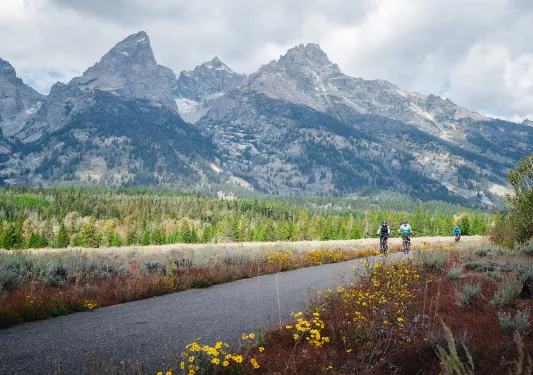 Three people biking with the Tetons in the background