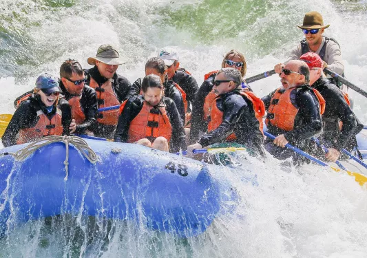 Group of men and women splashed during white water rafting