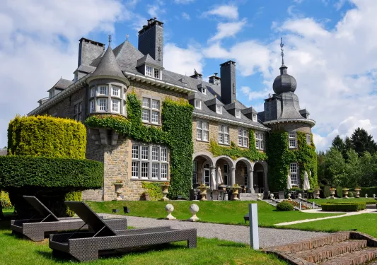 Stone building with trimmed hedges and gravel pathways