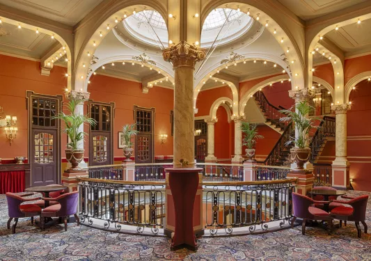Upper floor lobby with tables, chairs and a staircase