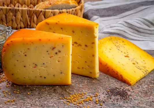Three slices of cheese from a wheel on a stone slab