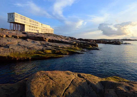 Long white building on large cliffs next to a body of water