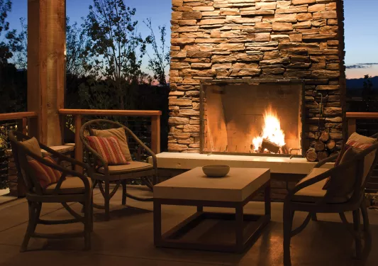 Four chairs in an outdoor patio in front of a stone fire place
