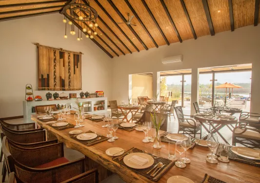 Indoor dining area with long, wooden tables, plates and glasses of wine on the tables