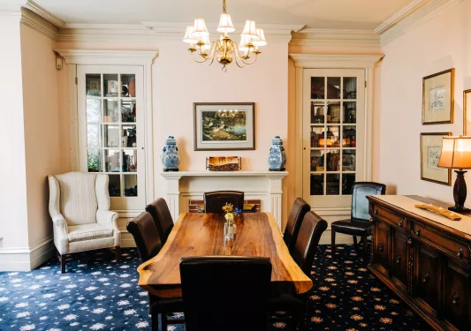 Indoor seating area with a wooden table and leather chairs, with painting on the walls
