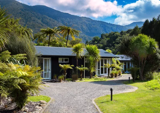 Blue building surrounded by tall plants and a gravel pathway