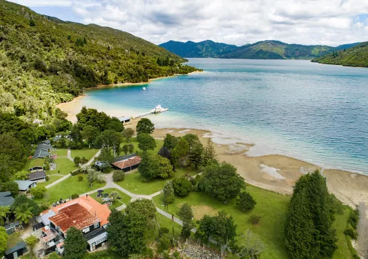 Coastline of a small beach  leadings towards smaller buildings 