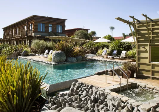 Outdoor pool in front of a wooden hotel building