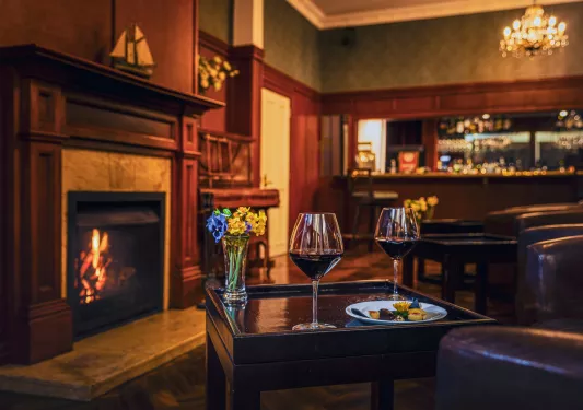 Table with two wine glasses in front of a fireplace in an indoor lounge
