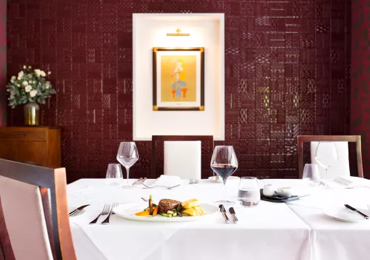 Dining table in a red room, with glasses of wine and a plate of food on the table