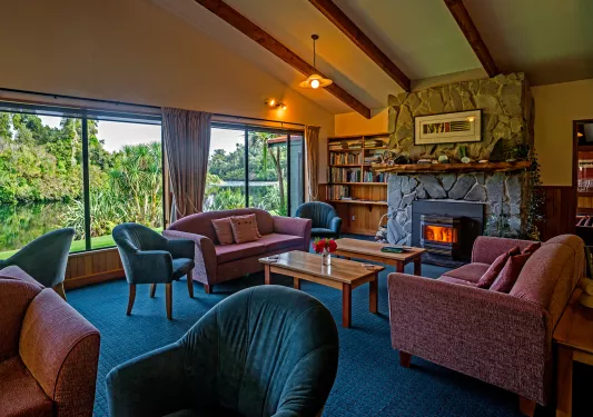 Seating area with red and green sofas and a stone fireplace in the center