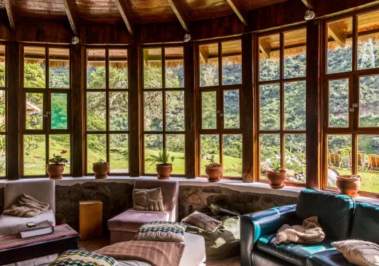 Cabin lounge area with cushioned seats and recliners, with large windows along the perimeter of the room