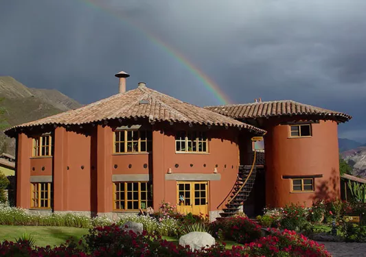 red house in front of a rainbow in the sky