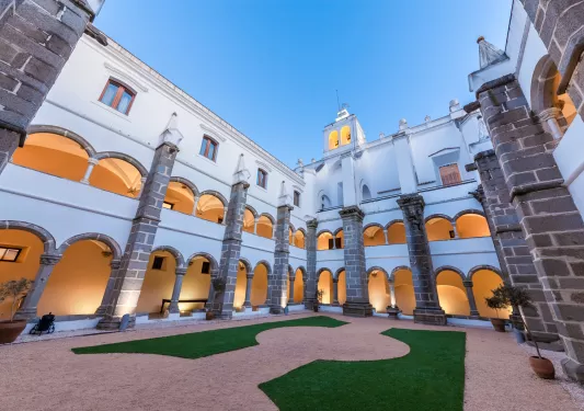 Exterior view of white hotel building with balconies that have large archways