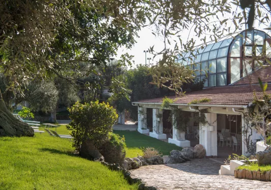 Exterior view of building with a greenhouse on the top floor, with a garden in front