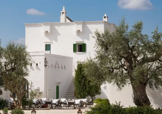White buildings with green accents, with an outdoor courtyard surrounded by trees