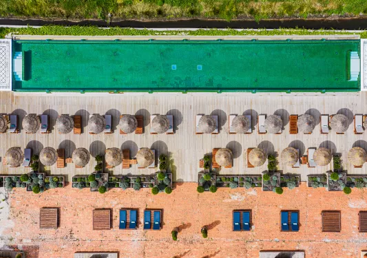 Sky view of outdoor pool with umbrellas and chairs on one side
