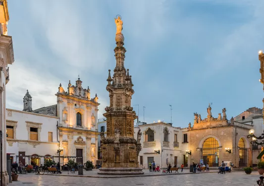 Town center with a pillar statue in the middle and people on ground level