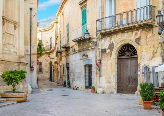 Alleyway of a town with outdoor seats and yellow buildings