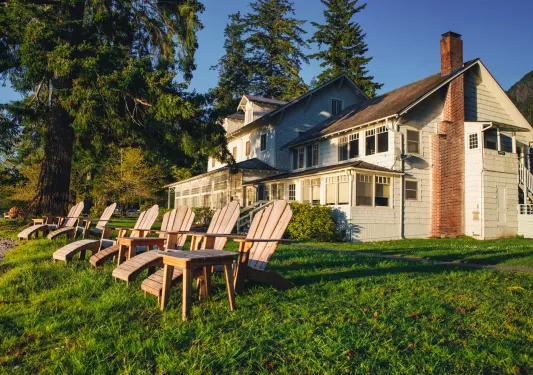 White house with a red chimney and six brown lawn chairs outside