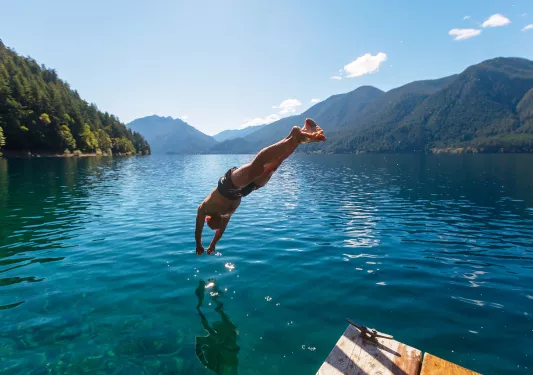 Man diving into a lake from a wooden port