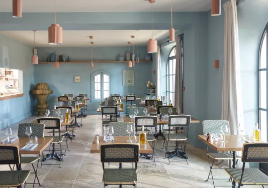 Indoor dining area with wooden chairs and tables, with bottles of alcohol on each table